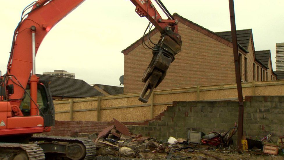 A digger removing parts of the peace wall