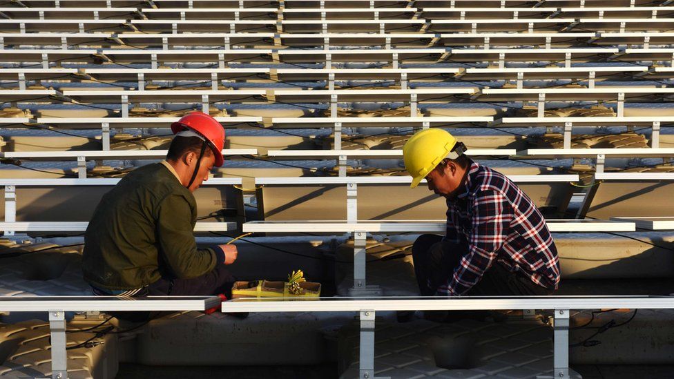 two men in hard has working on a solar power plant in China