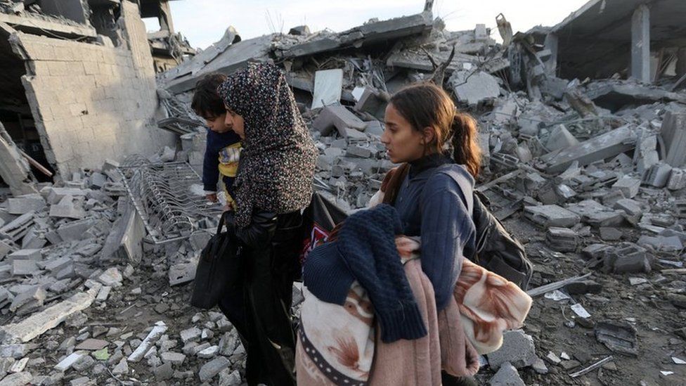 Palestinians walk past houses destroyed by Israeli air strikes in Rafah, southern Gaza Strip. Photo: 12 February 2024