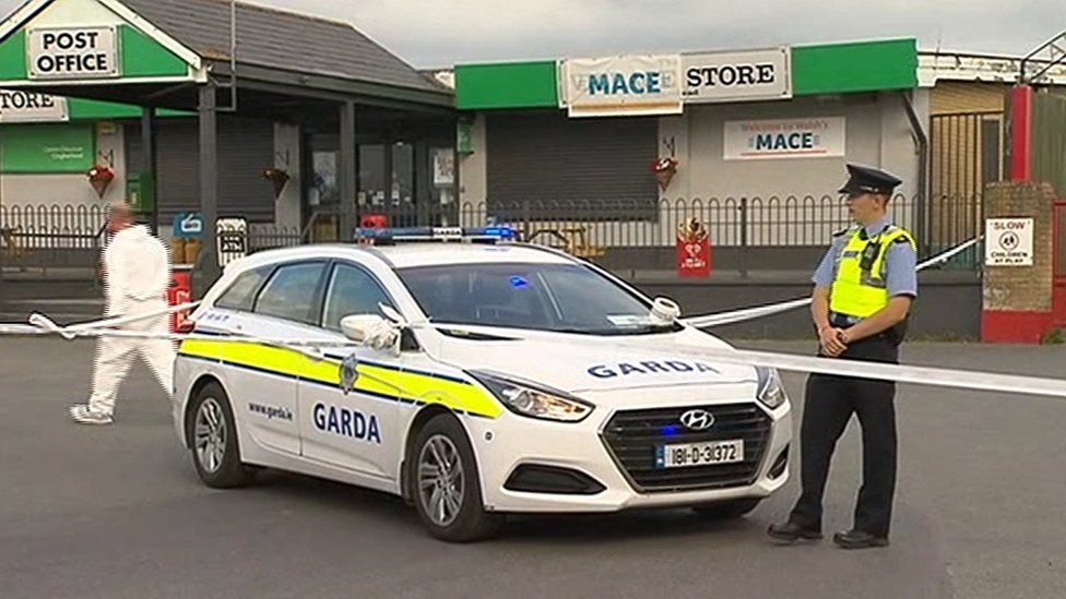 A garda stands next to a patrol car at the scene of the shooting
