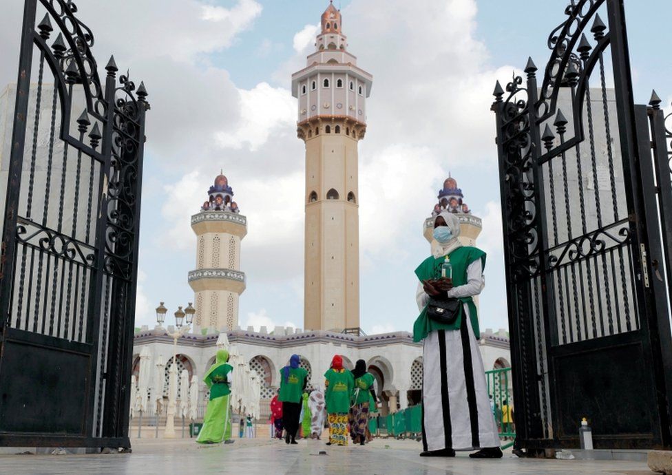 A woman stands with hand sanitiser at the entrance of the Great Mosque as hundreds of thousands of Senegalese Mouride Brotherhood pilgrims gather for the annual Grand Magal festival.