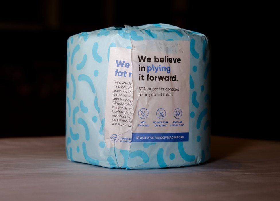 a toilet roll on a table which says on the packaging "we believe in plying it forward"