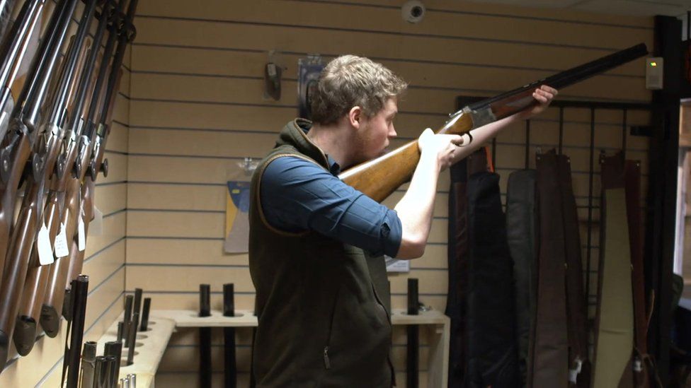 Jonathan Carter holds shotgun in the store he manages