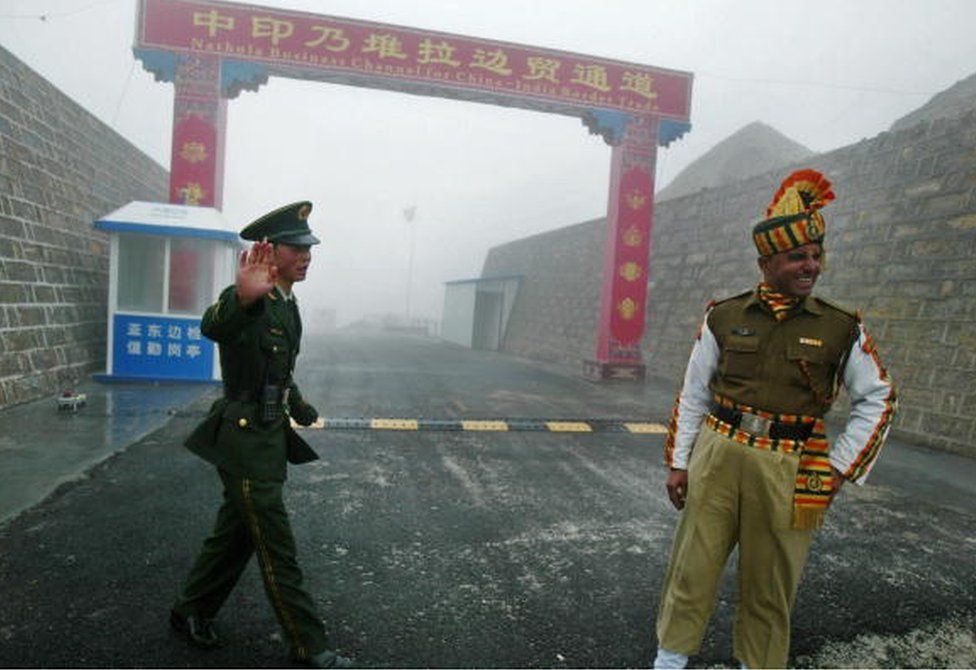 На этой фотографии, сделанной 10 июля 2008 г., китайский солдат (слева) и индийский солдат стоят на страже на китайской стороне древнего пограничного перехода Натху Ла между Индией и Китаем