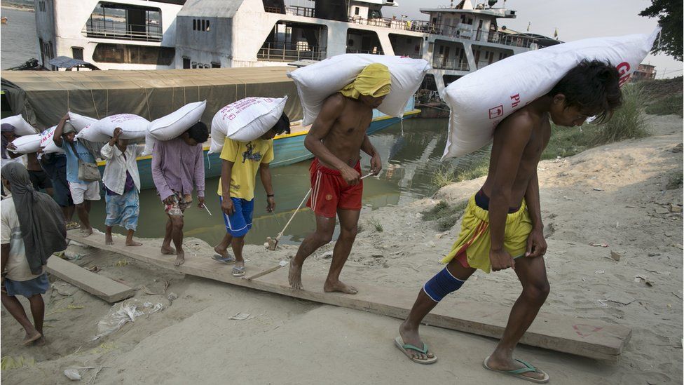 Workers carry a load off a boat on the Irawaddy River, Mandalay