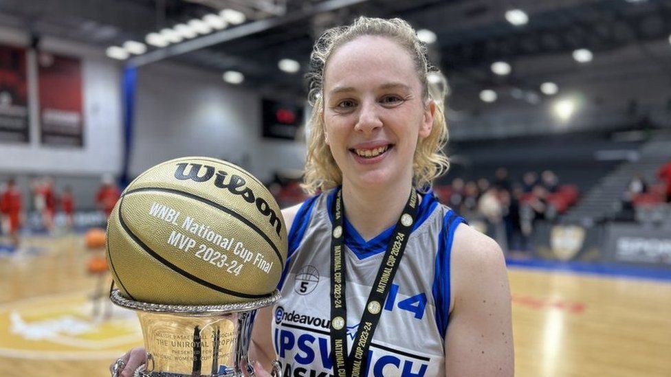 Basketball player holding a silver trophy with a ball on the top