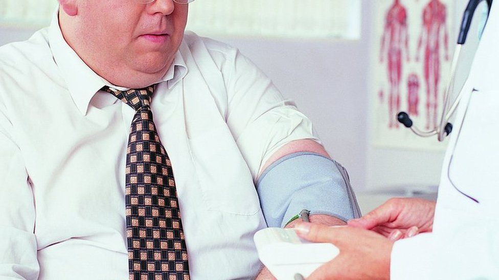 overweight person having blood pressure measured