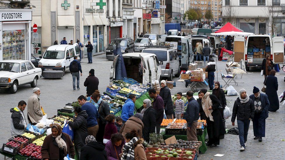 People shop at a market in the neighbourhood of Molenbeek, where Belgian police staged a raid following the attacks in Paris
