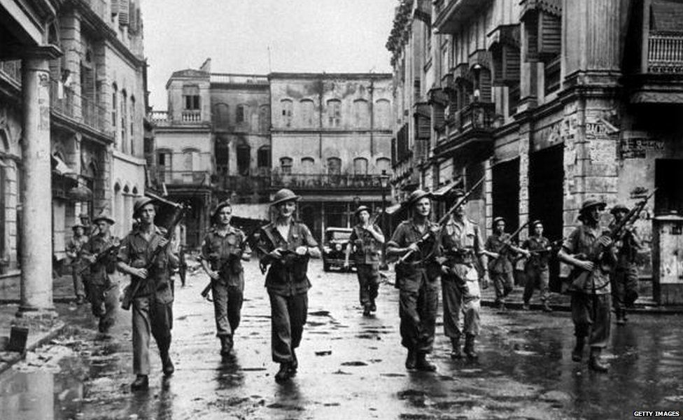 British troops in Calcutta, with rifles at the ready, clearing a street after Hindus and Muslims used firearms against each other. (Pho