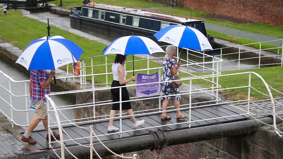 Visitors to the National Waterways Museum use umbrellas during a spell of rain