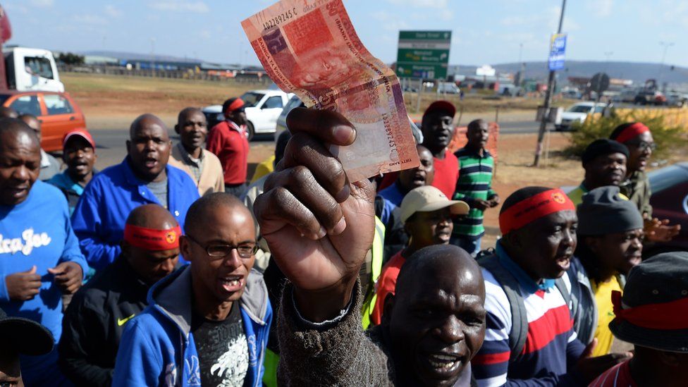 A factory work in South Africa holding up a banknote in Pretoria, South Africa - 2013