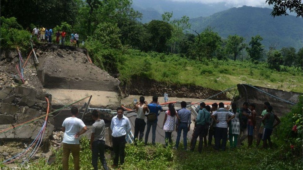 Bystanders look at a damaged bridge in the village of Garidhura some 35kms from Siliguri on July 1, 2015, after landslides struck the eastern state of West Bengal