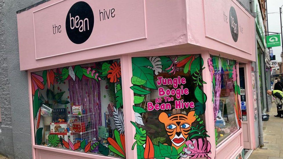 PInk corner shop with windows full of gifts and "Beehive" sign.