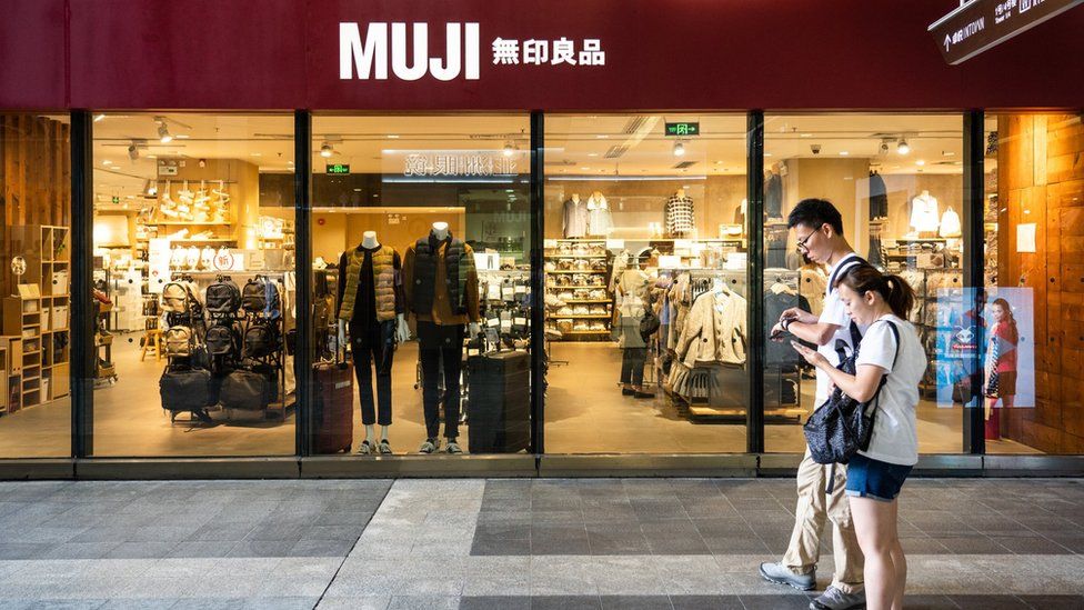 Pedestrians walk past a Japanese household and consumer goods retailer, Muji store in Shenzhen