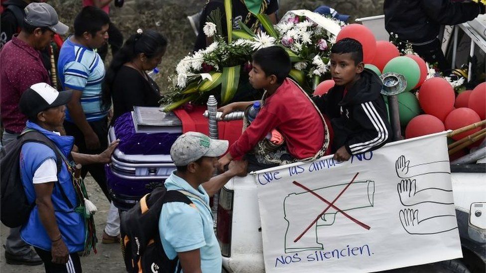 Colombian indigenous people hold a sign reading: "Let not the weapons silence us" during the funeral of Kevin Mestizo and Eugenio Tenorio,
