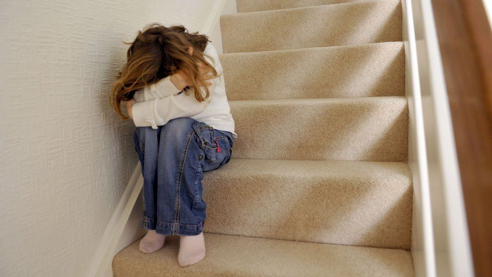 Child with her head in her arms on the stairs.