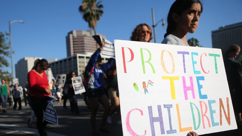 A child marches with a "protect the children" sign
