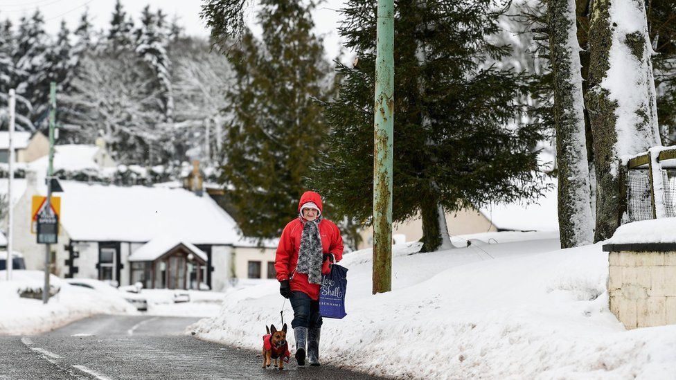 Woman walking dog through snow