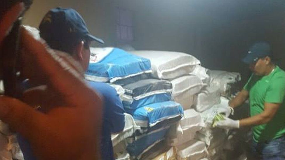 A picture shows police officers opening sacks filled with Venezuelan banknotes