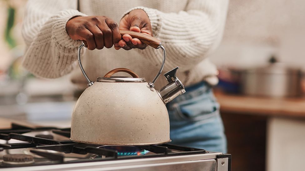 Woman boiling kettle connected  hob