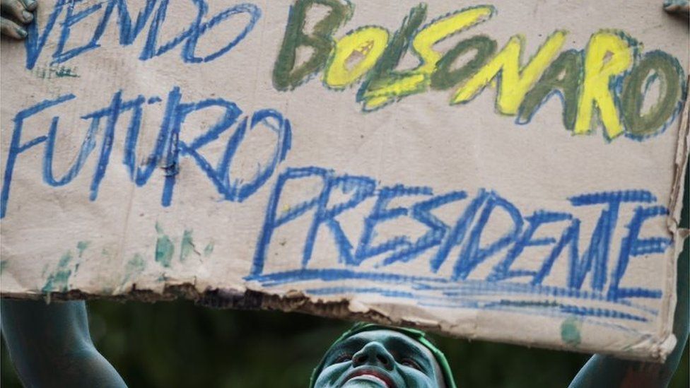 A man with his body painted in green holds a placard supporting a possible candidacy of congressman Jair Bolsonaro to the presidency during a demonstration against Brazilian President Dilma Rousseff, the federal government, ex-president Luiz Inacio Lula da Silva and the corruption cases being reported and currently investigated on March 13, 2016 in Manaus,
