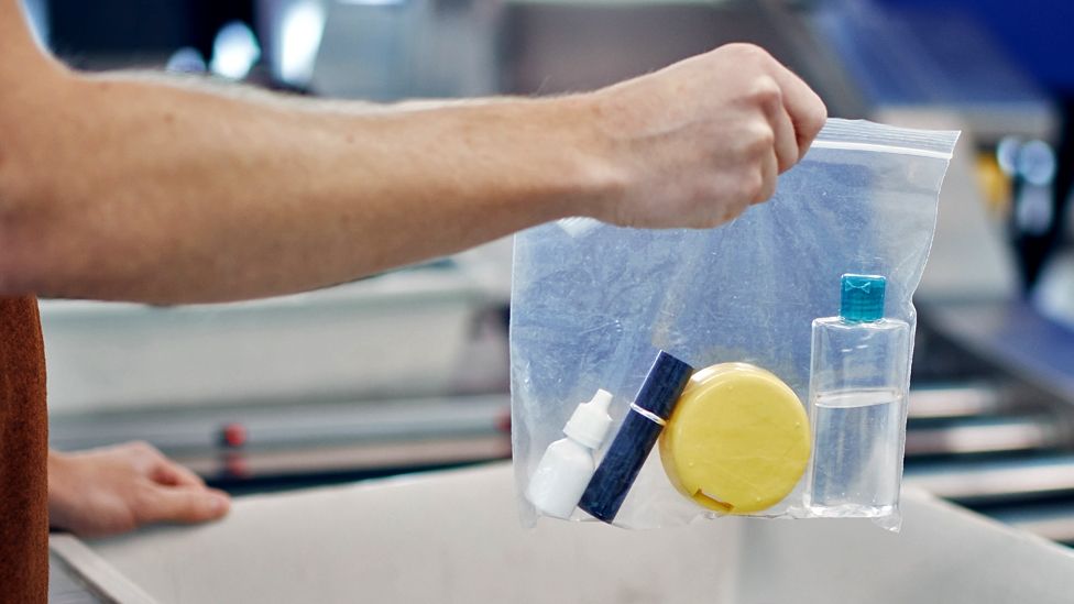 A person holds a bag of bottled liquids at airport security