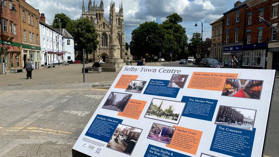 Selby Abbey, Market Cross and an information sign in the foreground