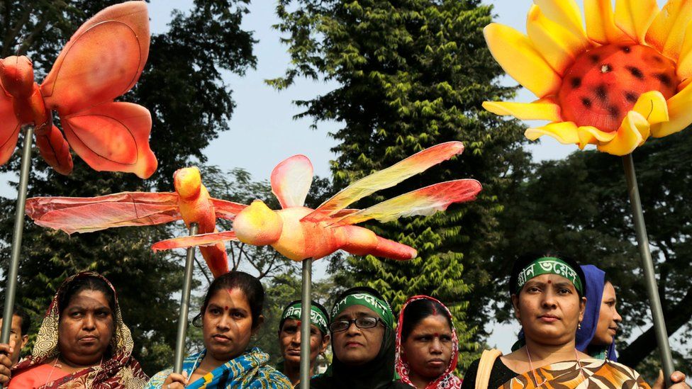 Participants carry symbolic insects and flowers as they demand action on climate change in Dhaka, Bangladesh, on Saturday