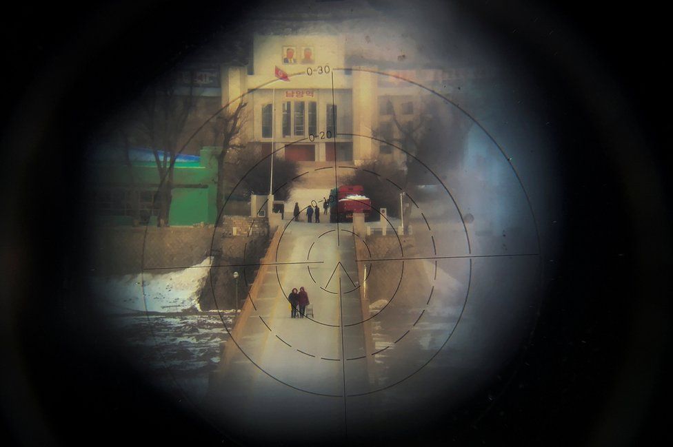 Women, photographed from the Chinese side of the border, are seen through binoculars.
