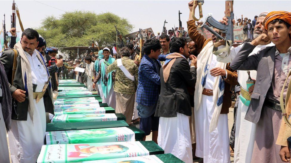 Men raise their rifles next to coffins in the northern Yemeni city of Saada on 13 August 2018