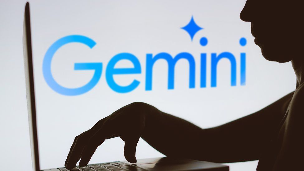 The Google Gemini logo in the background of a silhouette of a person using a laptop.