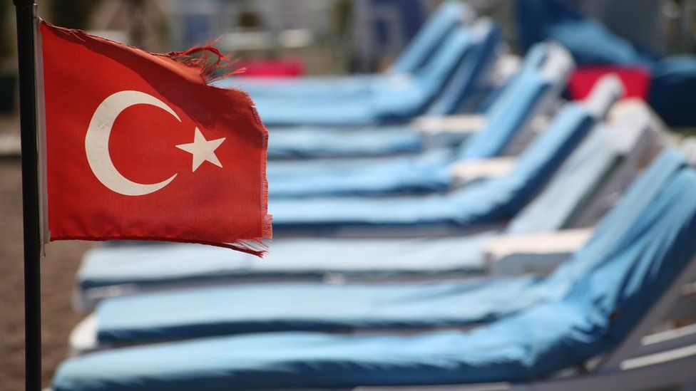 Turkish flag in front of empty sun beds