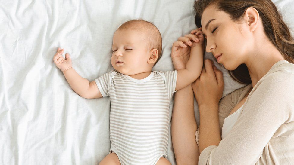 Mum sleeping next to baby.