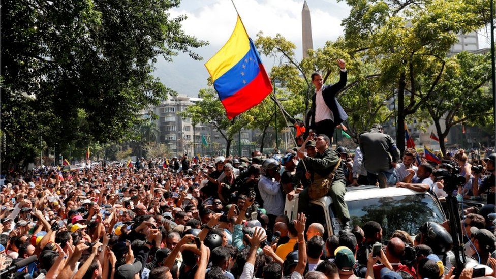 Juan Guaidó standing on top of a car amid street demonstrations in Caracas, 30 April 2019