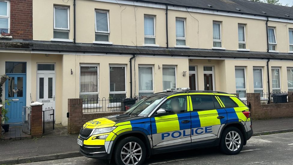 Murder scene with police car parked outside