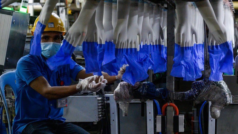 A worker inspects disposable gloves at a Top Glove factory in August