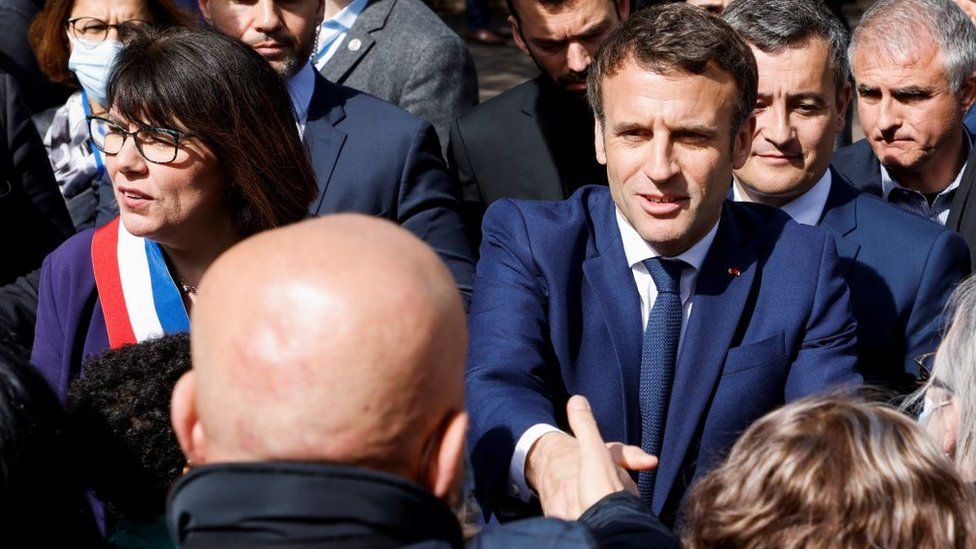 French President and liberal party La Republique en Marche (LREM) candidate for re-election Emmanuel Macron (2R) greets supporters as he arrives next to Denain's mayor Anne-Lise Dufour-Tonini (L)