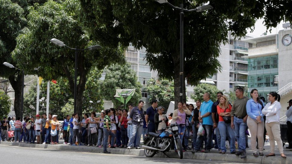 People queue to try to buy basic food items outside a supermarket in Caracas, Venezuela, April 28, 2016