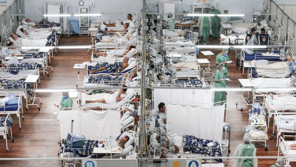Patients lie in beds while they receive aid from health workers at the Pedro DellAntonia Sports Complex field hospital