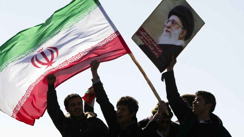 Iranians waving flag and picture of Ayatollah Ali Khamenei