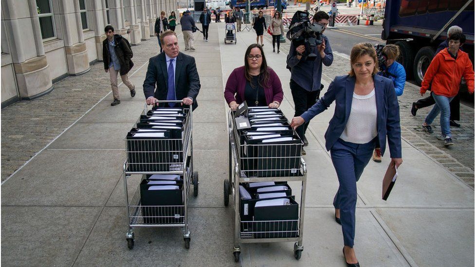 Staff and members of the prosecution team push carts full of court documents related to the U.S. v. Keith Raniere case as they arrive at the U.S. District Court for the Eastern District of New York