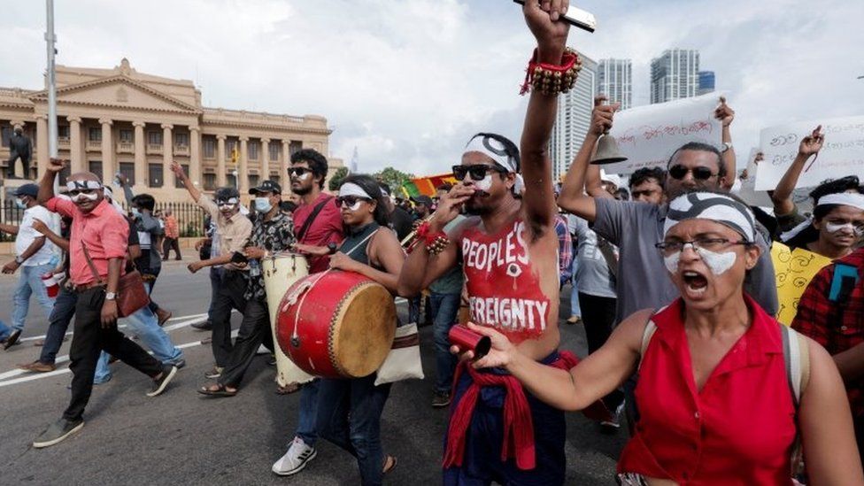 Protesters bang drums and raise their arms during a march against Sri Lanka's president on 10 April in Colombo