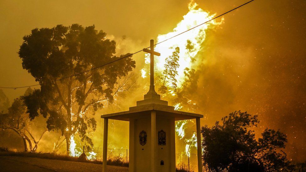 Flames rise next to a church during a fire in Pampilhosa da Serra