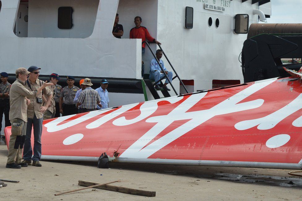 Foreign investigators (L) examine the tail of the AirAsia flight QZ8501 in Kumai on 12 January 2015, after debris from the crash was retrieved from the Java sea
