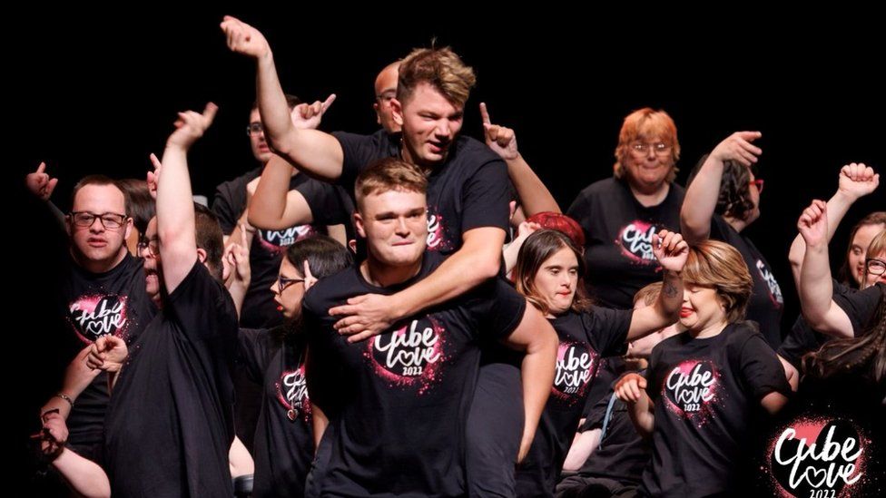 Young people in black "Cube Love" T-shirts on stage