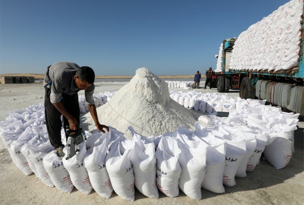 A worker prepares sacks of salt.