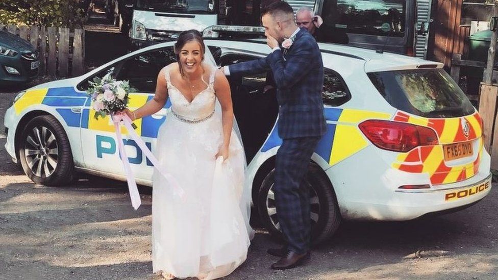 The newly weds getting out of a police car