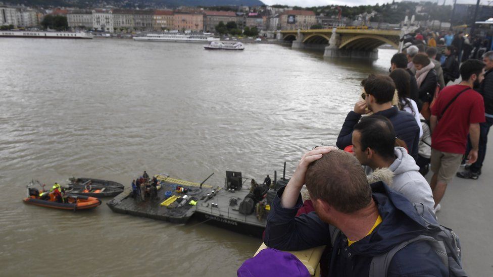People on Margaret Bridge watch operations to prepare the recovery of the capsized boat in Budapest