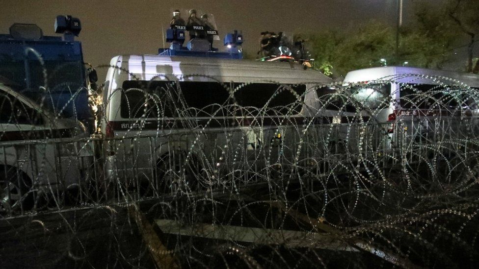 Thai police at a barricade of barbed wire and buses to halt protesters in Bangkok