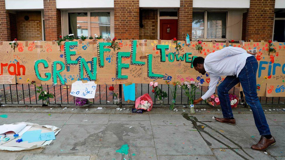 A man leaving flowers at a Grenfell Tower tribute